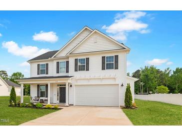 Charming two-story home featuring a well-manicured lawn, attached two-car garage, and inviting front porch at 214 Thumper Way, Clayton, NC 27520