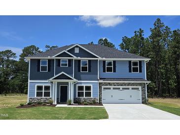 Two-story home featuring a gray shingled roof, blue siding, and a light gray stone garage at 29 High Hampton Way, Fuquay Varina, NC 27526