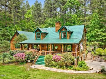 Charming log home features a green metal roof, landscaped front yard, and inviting front porch at 3009 Pleasant Hill Church Rd, Siler City, NC 27344