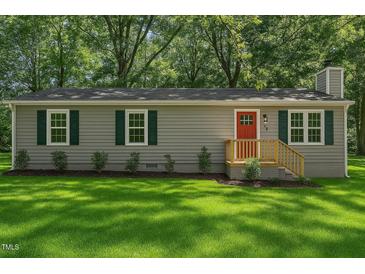 Charming home featuring gray siding, a bright red front door, and lush green lawn at 567 Howard Tant Rd, Zebulon, NC 27597