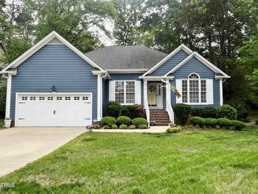 Charming single-story home featuring a blue exterior, white trim, a well-manicured lawn, and an attached two-car garage at 8712 Attingham Dr, Raleigh, NC 27615