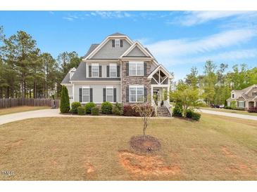 Charming two-story home with stone and gray siding, professional landscaping, and a well-manicured front yard at 101 Jewell Farm Lane, Holly Springs, NC 27540