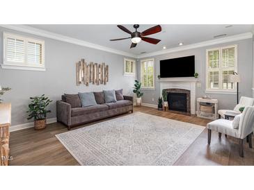 Cozy living room featuring a decorative fireplace, ceiling fan, and neutral color scheme at 1209 Shasta Daisy Dr, Wake Forest, NC 27587
