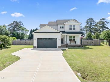 Beautiful two-story home with a long driveway, attached garage, covered porch and manicured front yard at 180 Packhouse Ct, Angier, NC 27501