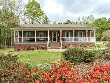 Charming brick home with inviting front porch and beautifully landscaped yard at 204 Wiley Oaks Dr, Wendell, NC 27591