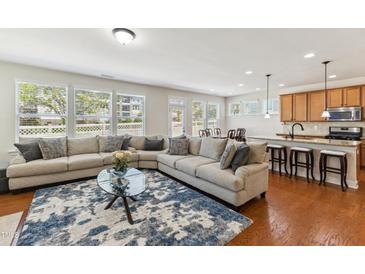 Bright living room with large sectional sofa, hardwood floors, and an adjacent kitchen with a breakfast bar at 205 Begen St, Morrisville, NC 27560