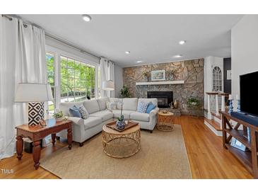Inviting living room features a stone fireplace, hardwood floors, and a large window with natural light at 305 Clarendon Cres, Raleigh, NC 27610