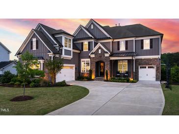 Stunning two-story home with a stone-accented entrance and well-manicured lawn at sunset at 3215 Bellamy Ridge Dr, Apex, NC 27523