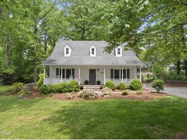 Charming home featuring a covered front porch, dormer windows, and a well-manicured lawn with lush landscaping at 404 Trappers Run Dr, Cary, NC 27513