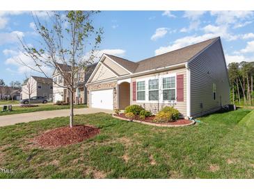 Inviting home exterior featuring stone accents, well-manicured lawn, and attached two car garage at 46 S Great White Way, Clayton, NC 27527
