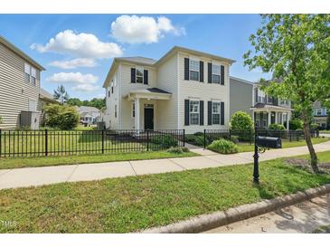 Charming two-story home featuring a well-manicured lawn and black metal fencing at 704 Moonbeam Dr, Raleigh, NC 27603