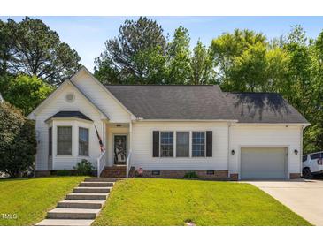 Charming white home featuring an attached garage, well-manicured lawn, and inviting front entrance at 8401 Hobhouse Cir, Raleigh, NC 27615
