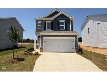 Charming two-story home with a two-car garage, and landscaped front yard against a beautiful blue sky at 152 Bruce Dr, Dunn, NC 28334