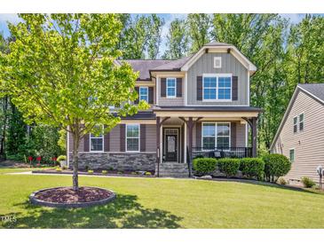 Inviting two-story home featuring a landscaped front yard and a charming covered porch with stone accents at 1557 Tice Hurst Ln, Apex, NC 27502