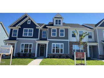 Modern townhome with a striking blue and gray exterior, complemented by lush green grass and professional landscaping at 1565 Wendell Valley Blvd, Wendell, NC 27591