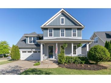 Charming two-story home featuring blue siding, a covered porch, and an attached two-car garage at 208 Vervain Way, Holly Springs, NC 27540