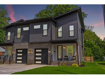 Modern townhome showcasing a striking gray facade, brick accents, and a well-manicured lawn at 2325 Sheffield Rd # 102, Raleigh, NC 27610