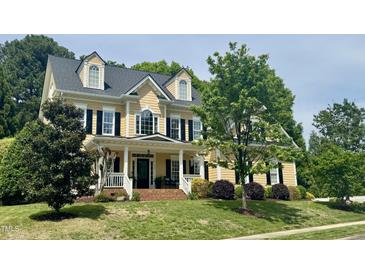 Charming two-story home featuring a welcoming front porch, well-manicured lawn, and beautiful landscaping at 402 Troycott Pl, Cary, NC 27519