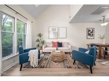 Bright living room featuring vaulted ceilings, large windows, stylish furniture, and wood-look flooring at 53 Forest Oaks Dr, Durham, NC 27705