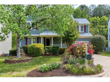 Charming blue two-story home with a lush front yard and a beautiful flower garden at 103 Trent Woods Way, Cary, NC 27519