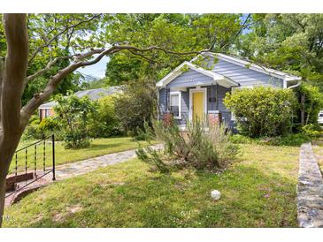 Charming exterior view of a single-story home with a yellow front door, stone walkway, mature landscaping, and a quaint front porch at 107 E Hammond St, Durham, NC 27704