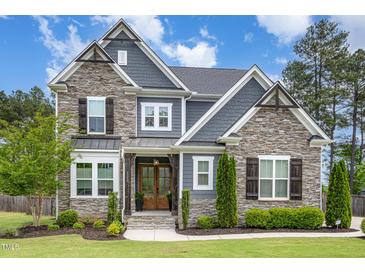 Charming two-story home featuring a stone facade, gray siding, wood accents, and a well-manicured front yard at 1112 Valley Rose Way, Durham, NC 27712