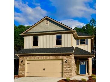 Two-story home featuring a brick facade, a two-car garage, complementary siding and a vibrant blue front door at 114 High Hampton Way, Fuquay Varina, NC 27526