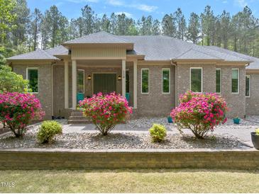 Charming brick home with a covered porch, flowering bushes, and meticulously maintained landscaping at 120 Wood Lake Dr, Fuquay Varina, NC 27526