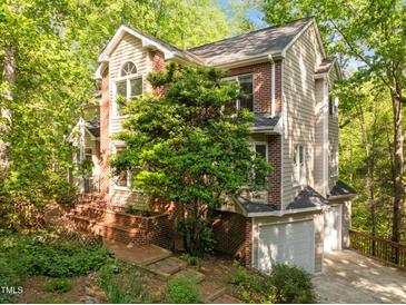 Charming home featuring a mix of brick and siding, set amidst lush trees and a brick walkway leading to the entrance at 205 Glenview Pl, Chapel Hill, NC 27514