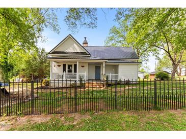 Charming white home with a black metal roof, front porch, and wrought iron fence at 2102 Courtland Dr, Sanford, NC 27330