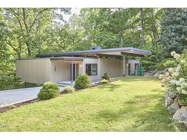 Modern home featuring a flat roof, covered parking, and lush landscaping with flowering shrubs at 220 Glenhill Ln, Chapel Hill, NC 27514