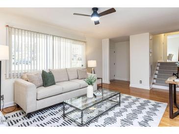 Bright living room with hardwood floors, a ceiling fan, modern furniture, and a large window for natural light at 3818 Hillgrand Dr, Durham, NC 27705