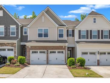 Charming townhome featuring a brick facade, a two-car garage, and beautifully landscaped front yard at 4137 Lofty Ridge Pl, Morrisville, NC 27560