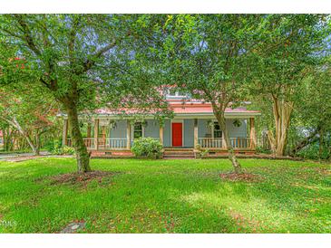 Charming two-story home with a red metal roof, a inviting front porch, and mature trees in a lush green yard at 429 N Asheboro St, Liberty, NC 27298