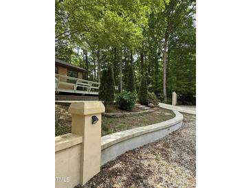 Landscaped front yard with a winding driveway, retaining wall, and a glimpse of the home's deck at 5601 Plum Nearly Ct, Raleigh, NC 27610
