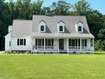 Charming home featuring a metal roof, classic white siding, and a welcoming front porch at 675 Anderson Creek Rd, Henderson, NC 27537