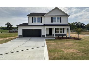 Two-story home featuring a black garage door and a covered front porch at 10 Silver Ct, Smithfield, NC 27577