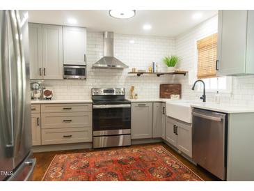 Updated kitchen with stainless steel appliances, white subway tile, and a farmhouse sink at 112 E Edgewood Dr, Durham, NC 27704