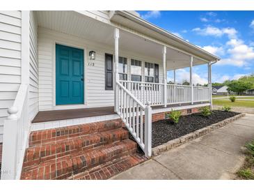 Charming front porch featuring a teal door, white columns, and brick steps at 112 Edmondson Dr, Willow Springs, NC 27592