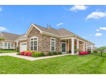 Beautiful single-story home featuring stone accents, well-manicured lawn, and vibrant flowerbeds at 122 Tall Timber Dr, Gibsonville, NC 27249