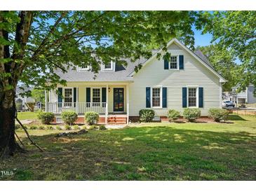 Charming home with white siding, blue shutters, inviting porch and mature landscaping at 1429 Raybon Dr, Wendell, NC 27591