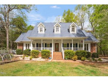 Charming one-story home featuring a welcoming front porch, dormer windows, brick stairs, and mature landscaping at 2925 Ericka Dr, Hillsborough, NC 27278