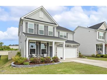 Charming two-story home with gray siding, stone accents, and a welcoming front porch with lush landscaping at 575 Dawley Dr, Fuquay Varina, NC 27526