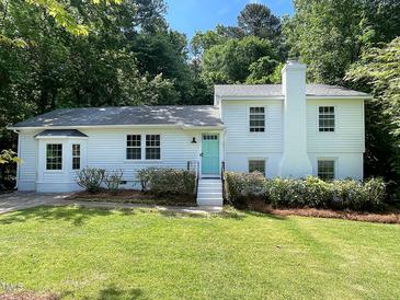 Charming white two-story home with a teal front door, mature landscaping, and a well-maintained lawn at 5817 Wintergreen Dr, Raleigh, NC 27609