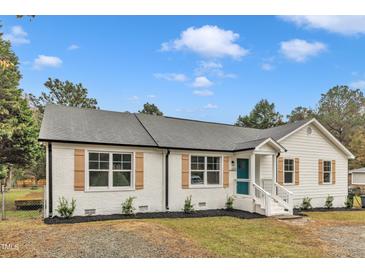 Charming, renovated single-story home featuring a teal front door and contrasting white brick and siding at 8201 Rhodes Rd, Apex, NC 27539