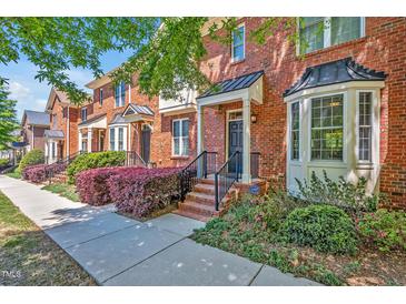 Charming brick townhomes with manicured landscaping and inviting front entrances on a sunny day at 110 Tressel Way, Durham, NC 27707