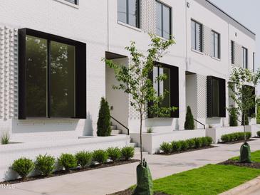 Newly constructed townhomes showcasing white brick facade, dark framed windows and manicured landscaping at 1308 Chamblee Hill Ct, Raleigh, NC 27608