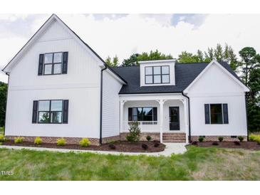 Charming two-story home featuring white siding, black trim, inviting front porch and a well-manicured lawn at 155 Diamond Creek Dr, Zebulon, NC 27597