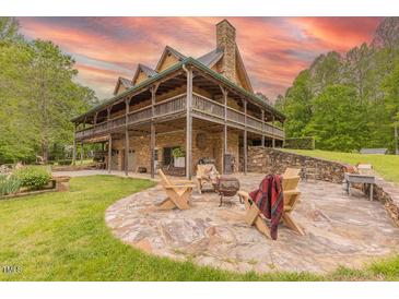 Charming stone home featuring a spacious patio with an outdoor fireplace and ample seating at 169 Country Brooke Lane Ln, Roxboro, NC 27574