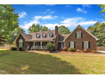 Charming brick home featuring a covered porch,dormer windows, and manicured landscaping at 3909 Inland Ct, Raleigh, NC 27606